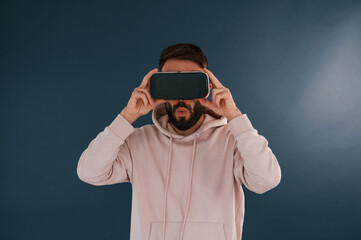 In VR glasses. Handsome man is in the studio against blue background