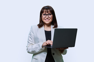 Mature business woman with laptop, on light studio background