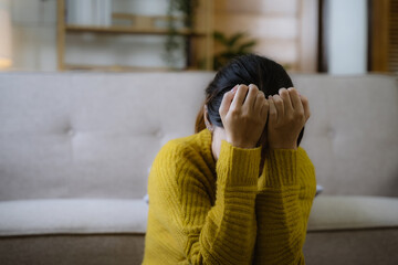 young women touching head, feeling headache, migraine, sitting on couch at home. Depressed young...