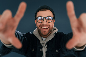 Making the photo by hands, pretending. Smiling. Handsome man is in the studio against blue background