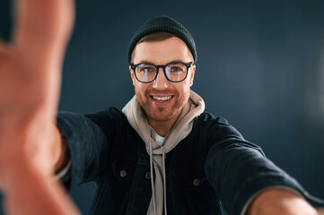 Handsome man is in the studio against blue background, Making selfie