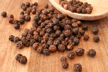 Black peppercorns on a spoon