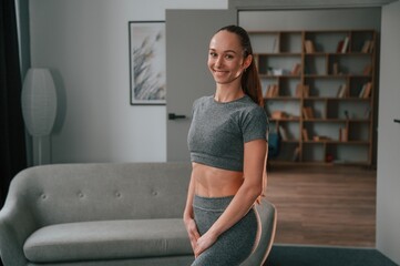 In apartment. Young woman in yoga clothes doing fitness indoors