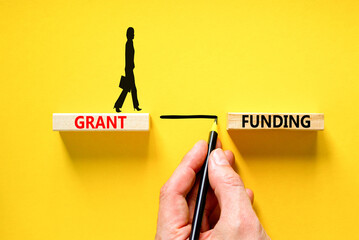 Grant funding symbol. Concept words Grant funding on wooden blocks. Beautiful yellow table yellow...
