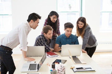 Creative business people using laptop in board room