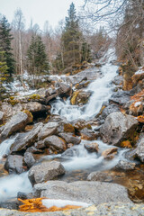 Waterfall in the valley of Molières, Valle de Aran, Catalonia, Spain. Snowy autumn, colorful mountain landscape with snow-capped mountains, wild environment of the Pyrenees.