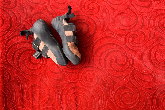 A pair of worn rock climbing shoes rests on a br ight red crash pad at Gloria's Rocks, Flags
