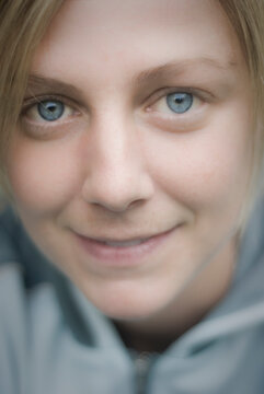 Soft close up portrait of a content young woman with blue eyes wearing a blue fleece jacket.