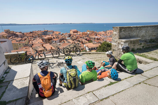 Bikers sitting on stairs and looking a congested town by sea