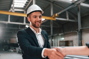 Fototapeta premium Handshake with partner. Manager in black formal wear at the factory
