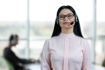 Portrait of asian woman customer support wearing headset. Office setting background.