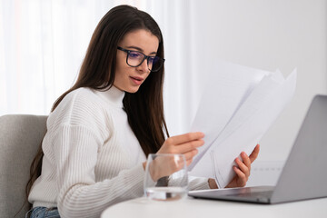 Business woman in white shirt using laptop computer and checking documents.