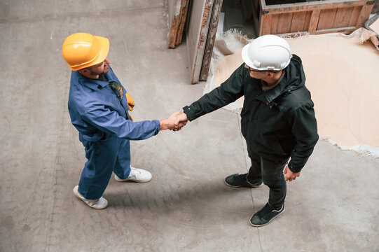 Two industrial workers are doing handshake. Top view. Successful agreement