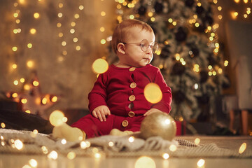 In glasses. Cute little baby is at home. New year decorations. Conception of holidays