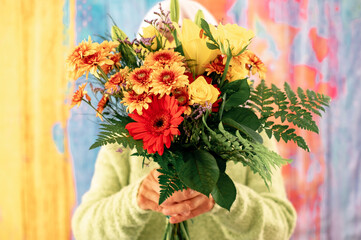 Senior woman hidden by a bouquet of flowers isolated on colorful background. Valentine's Day Women's Day birthday holiday party.