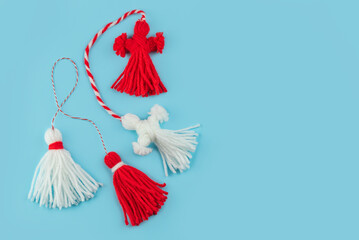 Traditional Martisor - symbol of holiday 1 March, Martenitsa, Baba Marta, beginning of spring and seasons changing in Romania, Bulgaria, Moldova. Greeting and post card for holidays. Blue background.