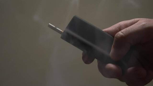 Close-up of a man's hand holding a tobacco heating device.