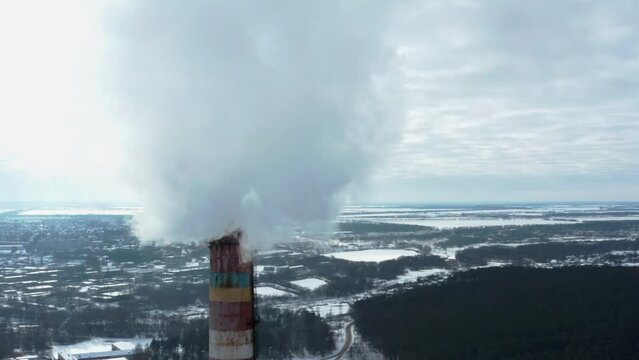Smoking chimney on the background of the city in winter. Environmental pollution from emissions into the atmosphere. Aerial view of atmospheric emissions. Ukraine 2022, the city of Shostka.