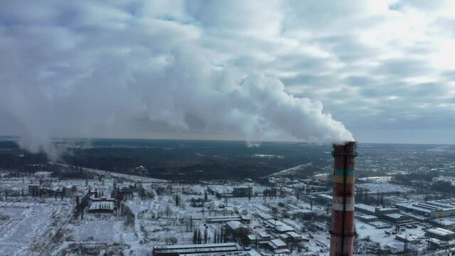 Smoking chimney on the background of the city in winter. Environmental pollution from emissions into the atmosphere. Aerial view of atmospheric emissions. Ukraine 2022, the city of Shostka.