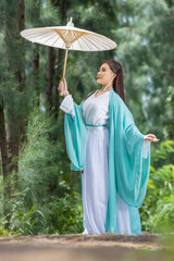 Young beautiful Asian woman dressed in ancient Chinese warrior style with ancient fan. cute girl in green dress
