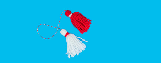 Traditional Martisor - symbol of holiday 1 March, Martenitsa, Baba Marta, beginning of spring and seasons changing in Romania, Bulgaria, Moldova. Greeting and post card for holidays. Blue background. 