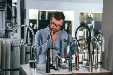 A large selection of water faucets. Man chooses a products in a sanitary ware store