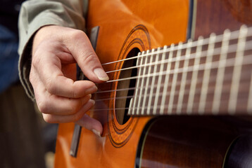 Male hands playing acoustic guitar, close up.  Teacher is giving guitar lesson