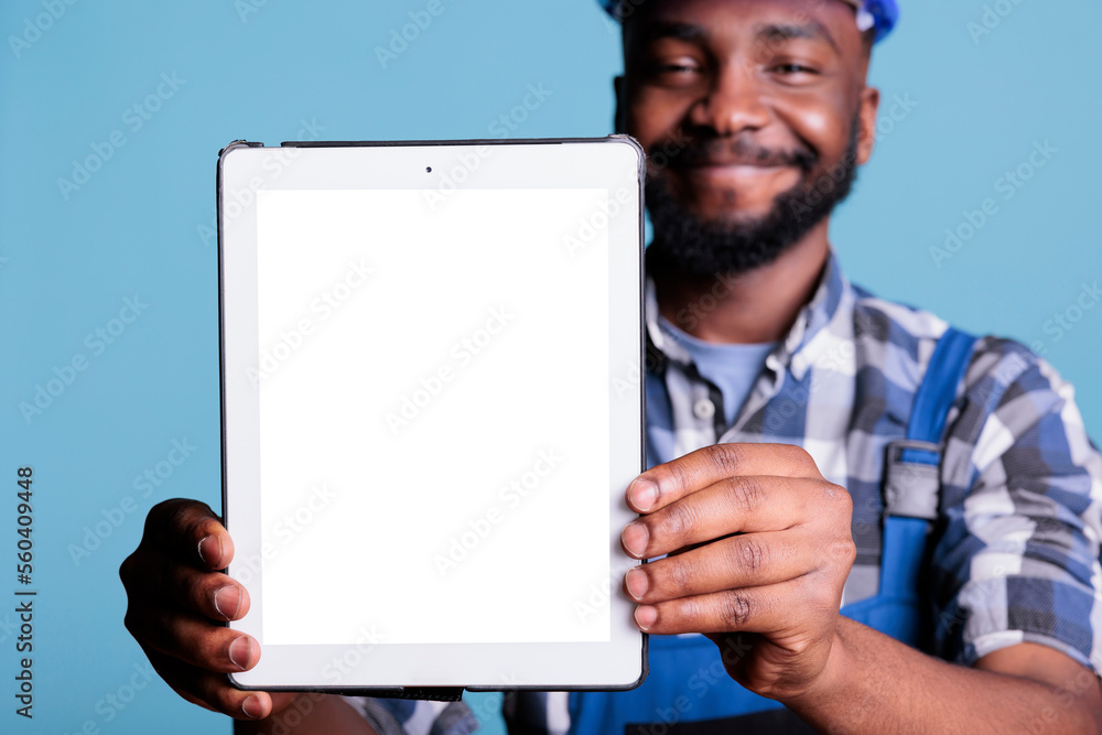 Poster smiling construction worker holding digital tablet with blank screen for advertising in front of cam