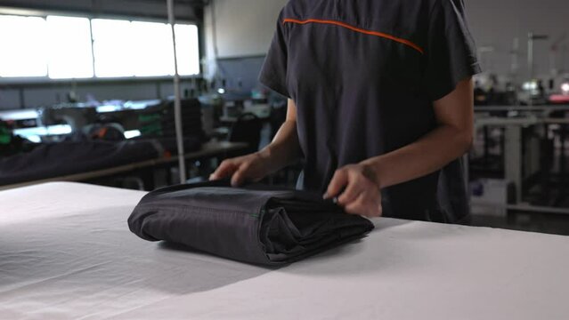 A girl irons work clothes on an ironing board with an iron in the room.