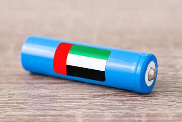 Close up shot of li-ion battery on wooden table with flag of United Arab Emirates on its side. Concept of producing batteries in UAE, origin of batteries