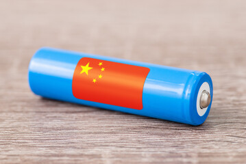 Close up shot of li-ion battery on wooden table with flag of China - world`s leading producer of...