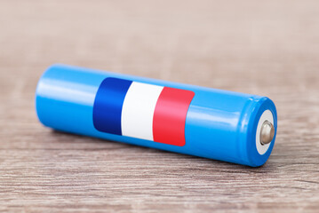 Close up shot of li-ion battery on wooden table with flag of France on its side. Concept of producing batteries in France, origin of batteries