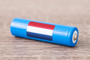 Close up shot of lithium battery on table with flag of Netherlands on its side. Production of li-ion batteries in Netherlands concept