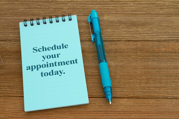 Schedule your appointment today on a notepad on wood desk