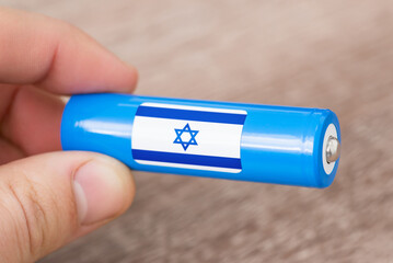 Man holding rechargeable li-ion battery with flag of Israel. Production of lithium batteries in...