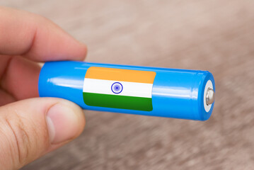 Man holding rechargeable li-ion battery with flag of India. Production of lithium batteries in India
