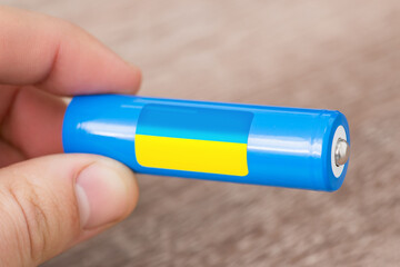 Man holding rechargeable li-ion battery with flag of Ukraine. Production of lithium batteries in...