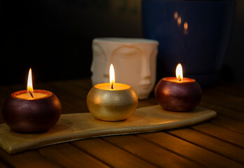 candles in the dark on wooden table and Buddha face background, spa, relaxation, beauty, calmness 