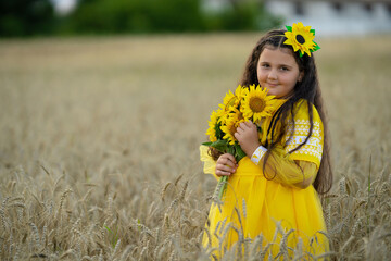 A girl in a wheat field with a bouquet of sunflowers.