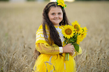 A girl in a wheat field with a bouquet of sunflowers.
