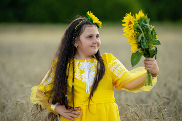 A girl in a wheat field with a bouquet of sunflowers.