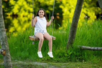 A six-year-old girl swings on a swing by the river.