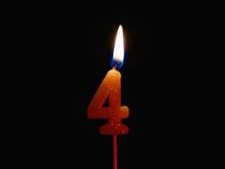 Burning birthday candle isolated on black background, number 4