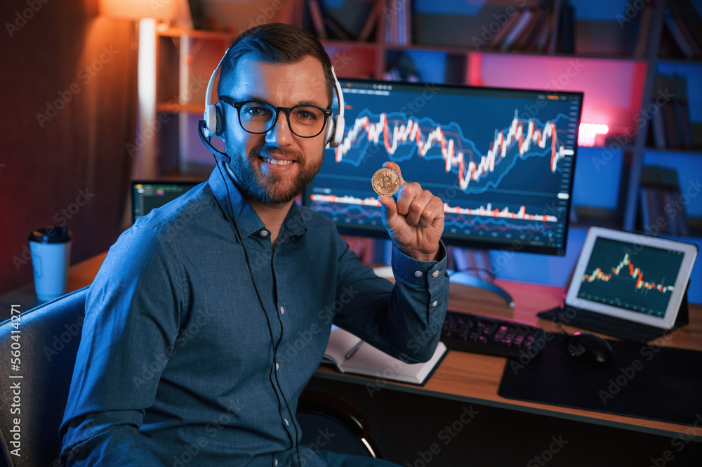 Poster holding bitcoin. stock trader is working by pc indoors. conception of exchange and money