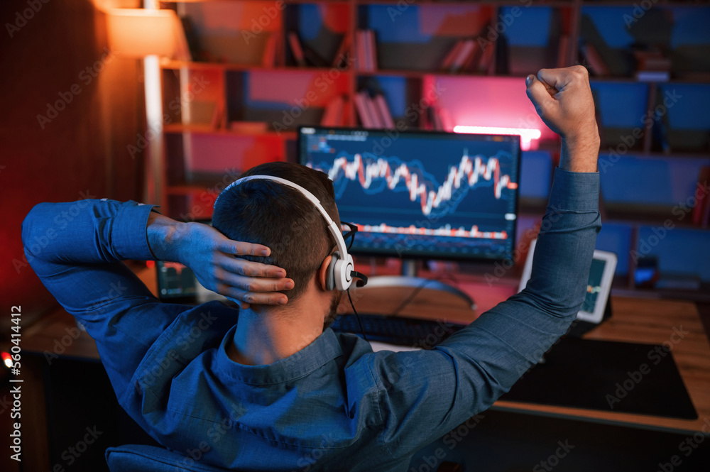 Poster view from behind. stock trader is working by pc indoors. conception of exchange and money