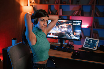 Young pretty female gamer is playing shooter. Neon lighting