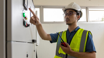 Electrical engineer working in control room. Electrical engineer man checking Power Distribution Cabinet in the control room