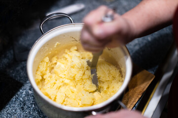 Mashing potatoes with a hand in a pot - sometimes called smashed potatoes