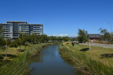 a river and some green areas near an urbanization of buildings and houses