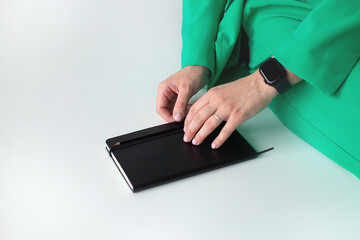 A black notebook in the hands of a woman. On white background. Planning tools.
